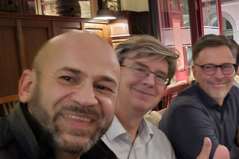 Drei Männer an einem Tisch in einem Regensburger Brauhaus, lächelnd in die Kamera