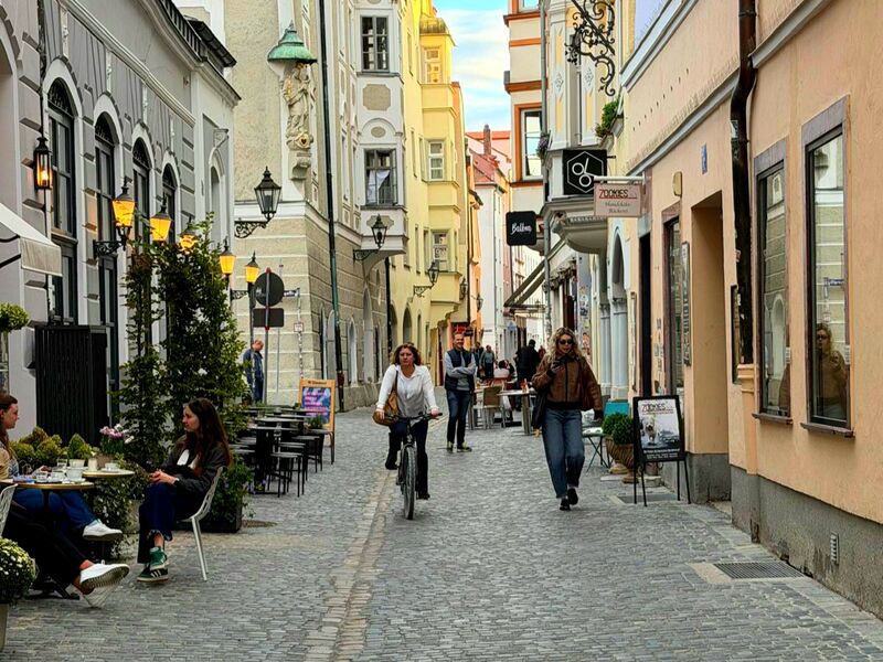 Enge Altstadtgasse mit Cafétischen, Laternen und Ladenschildern