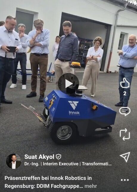Videovorschau: die Fachgruppe steht um einen blauen Transportroboter auf dem Werkhof, der Roboter zieht einen Anhänger