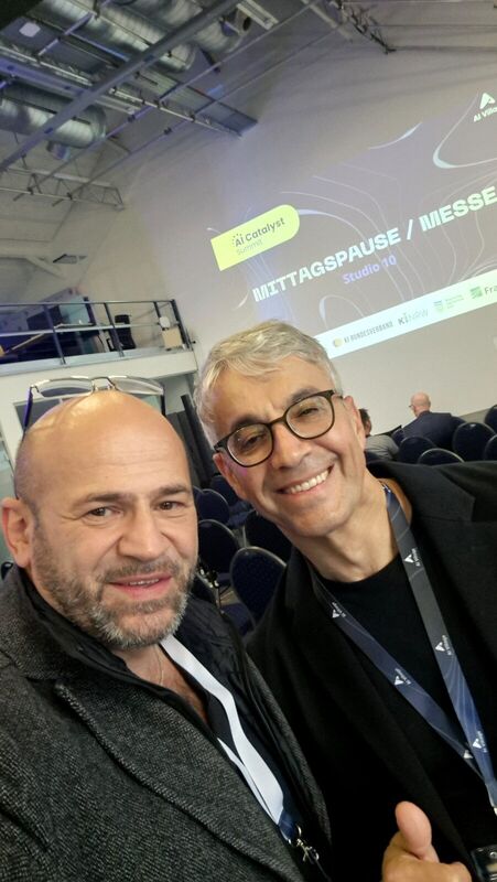 Suat Akyol mit Edip Saliba von Microsoft, Selfie vor der Leinwand mit dem Hinweis auf Mittagspause und Messe
