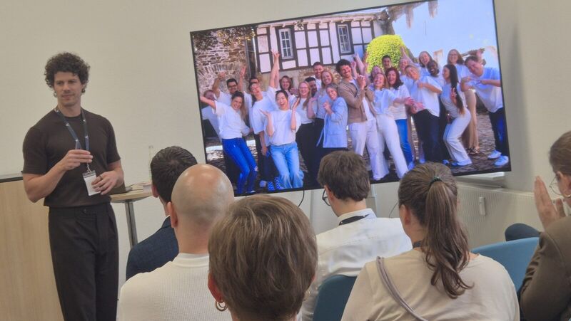 Bastian Sens bei seiner Masterclass vor einem Bildschirm mit einem Teamfoto