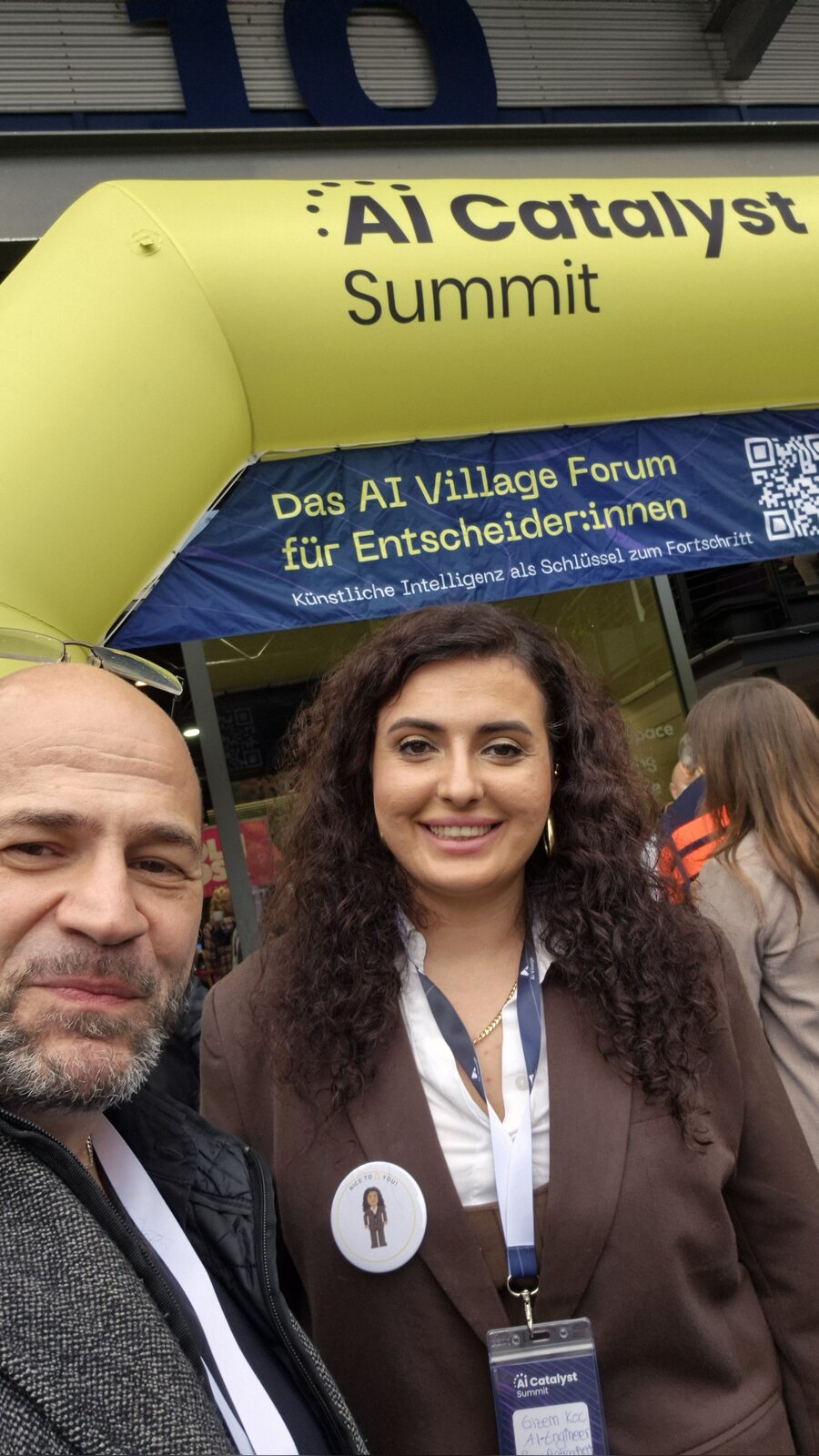 Suat Akyol mit Gizem Koç, Selfie unter dem Eingangsbogen des AI Catalyst Summit im AI Village Hürth